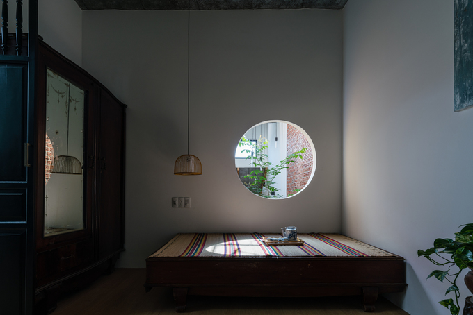 Hình ảnh một phòng ngủ đậm chất hoài cổ với giường gỗ, tủ gỗ, cửa sổ tròn, chiếu lác