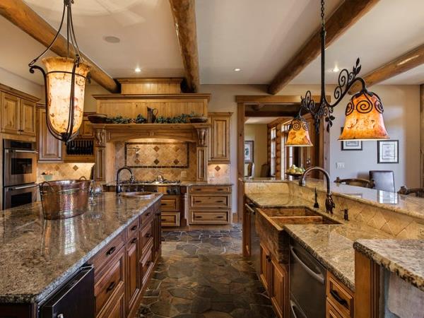 Hình ảnh một phòng bếp với tông màu vàng nâu chủ đạo, bàn bếp ôp đá granit, sàn nhà lát đá tự nhiên, đèn trang trí cổ điển