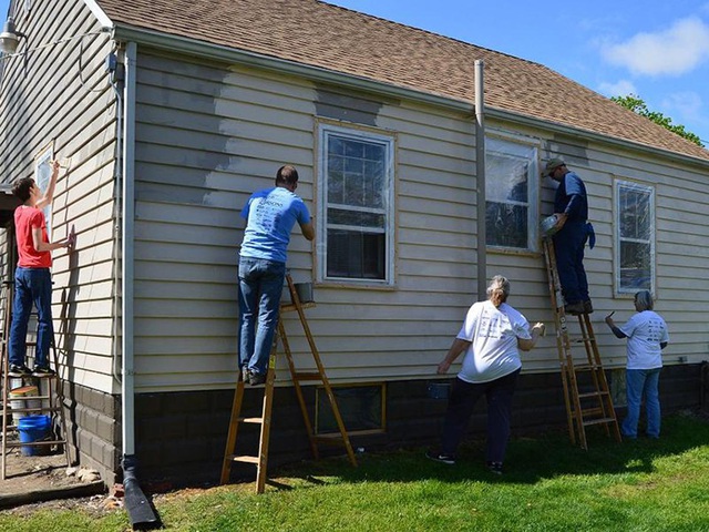 Hình ảnh một nhóm người đàn ông đang sơn sửa bên ngoài một ngôi nhà