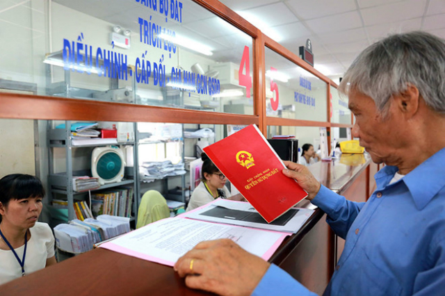 Hình ảnh một người đàn ông lớn tuổi mặc áo màu xanh, cầm sổ đỏ làm thủ tục ở cơ quan thuế