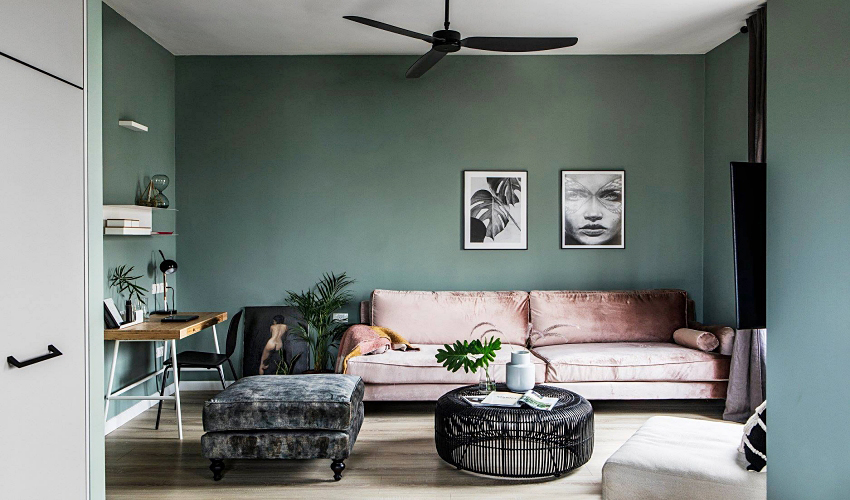 Hình ảnh phòng khách căn hộ 70m2 với tường xanh lá nhạt, sofa màu hồng phấn, bàn trà đen độc đáo, cạnh đó là bàn làm việc bằng gỗ, cây xanh trang trí