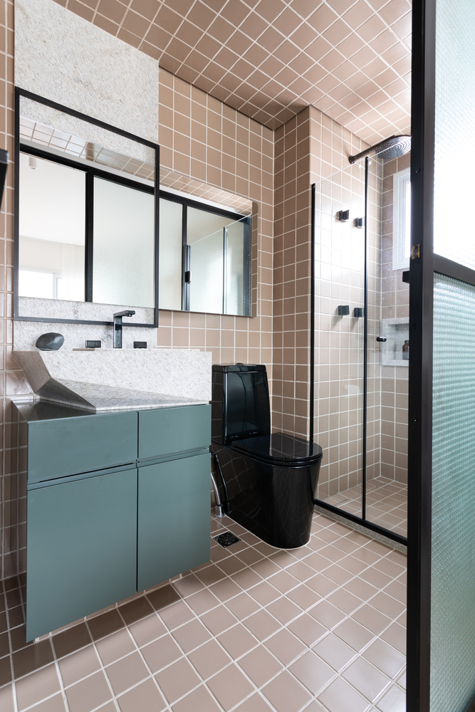 Hình ảnh toàn bộ tường, trần và sàn phòng tắm được ốp gạch màu hồng đất nhẹ nhàng, tủ lưu trữ màu xanh ngọc, chậu đá granite bất đối xứng