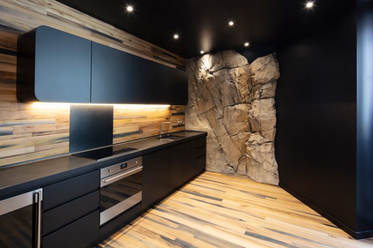 Hình ảnh một phòng bếp ấn tượng với tủ màu đen, tường ốp gỗ, điểm nhấn là bức tường đá