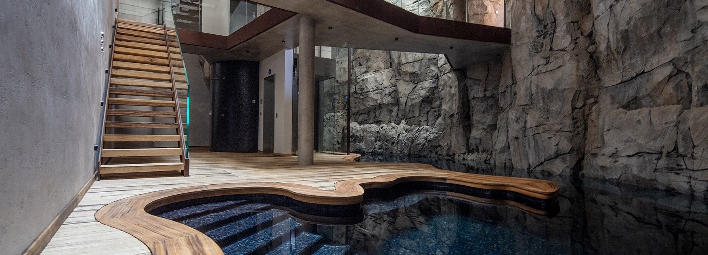 Hình ảnh bên trong biệt thự với cầu thang gỗ bậc hở, bể nước độc đáo, sàn lát gỗ, tường bê tông xám