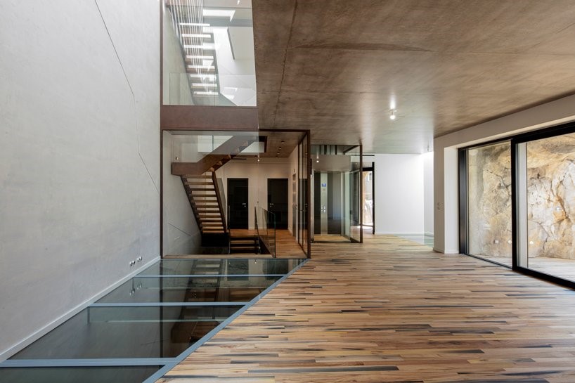 Hình ảnh hành lang biệt thự với sàn lát gỗ, một phần sàn lát kính, cầu thang đẫn lên tầng trên