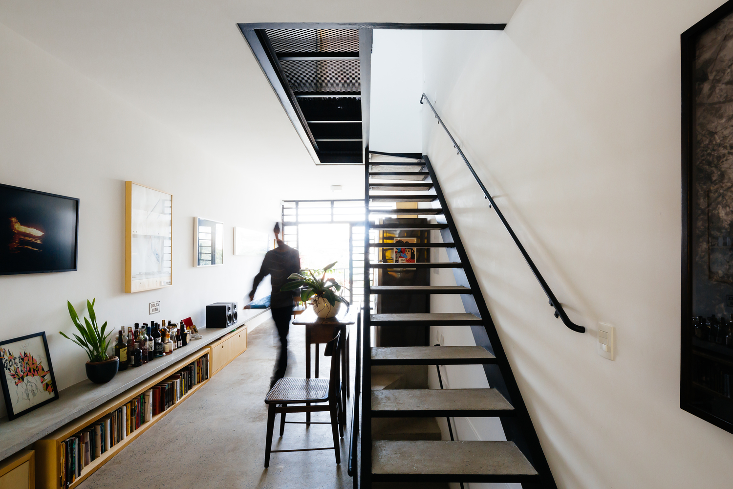 Hệ cầu thang kim loại bậc hở thông thoáng được bố trí sát tường nhà, giúp tiết kiệm diện tích.