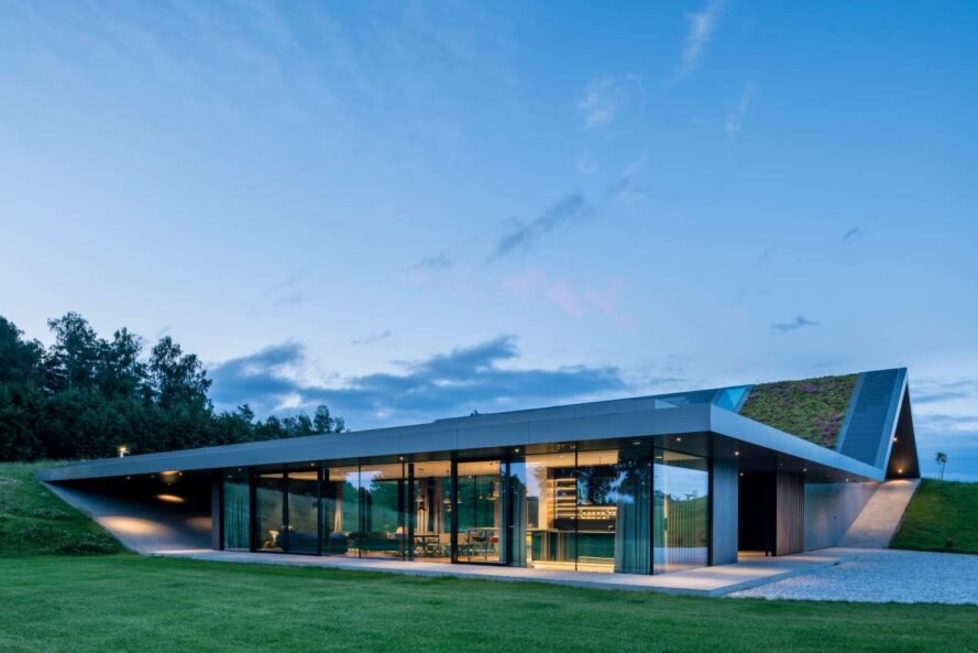 Hình ảnh mặt tiền ngôi nhà hình chữ L với tường kính trong suốt, mái phủ cỏ xanh