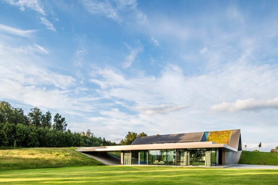Hình ảnh toàn cảnh một ngôi nhà có thiết kế độc đáo với phần mái phủ cỏ xanh, tường kính trong suốt