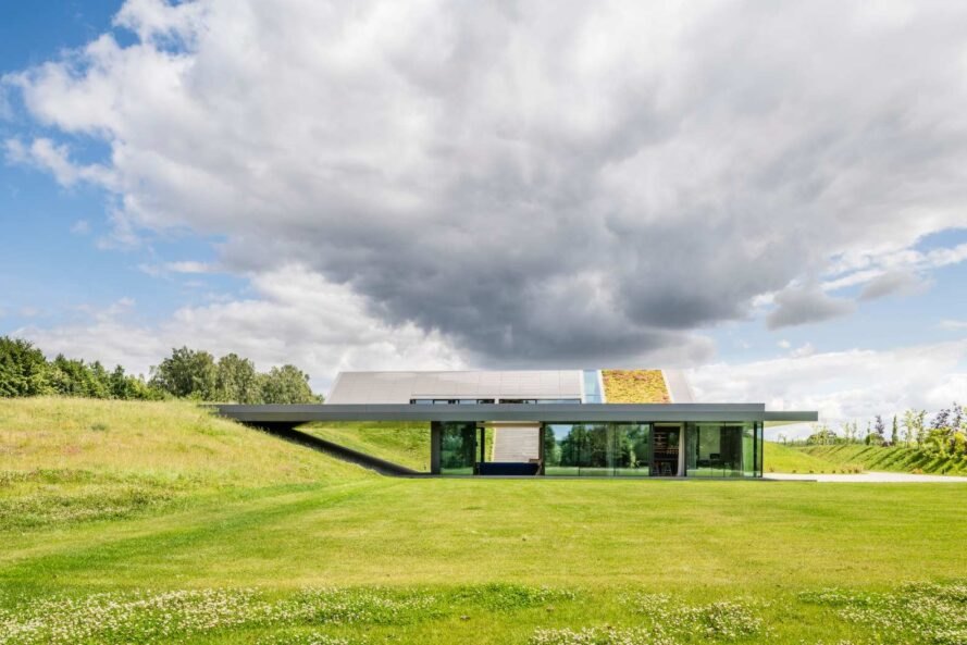 Hình ảnh một ngôi nhà độc đáo tọa lạc trên đồi cỏ xanh mướt với phần mái bê tông xám nhô lên khỏi mặt đất