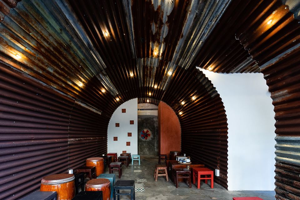 Hình ảnh không gian bên trong quán cà phê Bông với những tấm tôn tròn lượn sóng kết hợp với hệ thống đèn chiếu sáng bắt mắt, phía dưới đặt bàn ghế gỗ mộc mạc