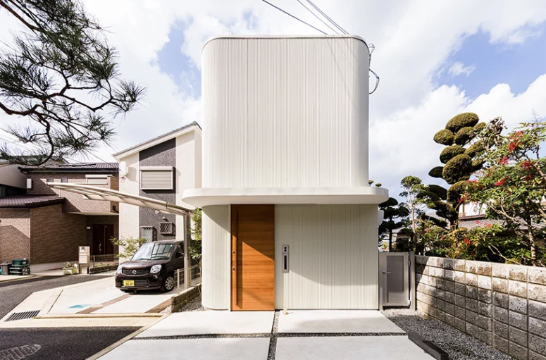 Hình ảnh toàn cảnh ngôi nhà Nhật ấn tượng với sắc trắng chủ đạo, hình khối kiến trúc chắc khỏe, cửa ra vào bằng gỗ ấm áp