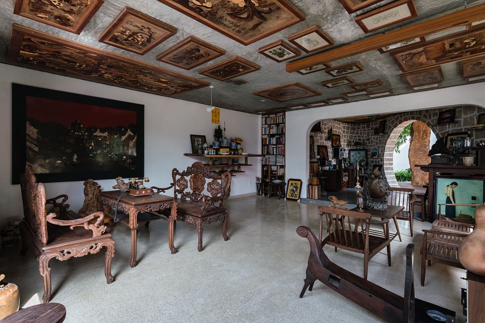 Hình ảnh phòng khách và khu thờ cúng bên trong nhà gỗ với bàn ghế gỗ chạm trổ tinh xảo, tường nhà trang trí ấn tượng