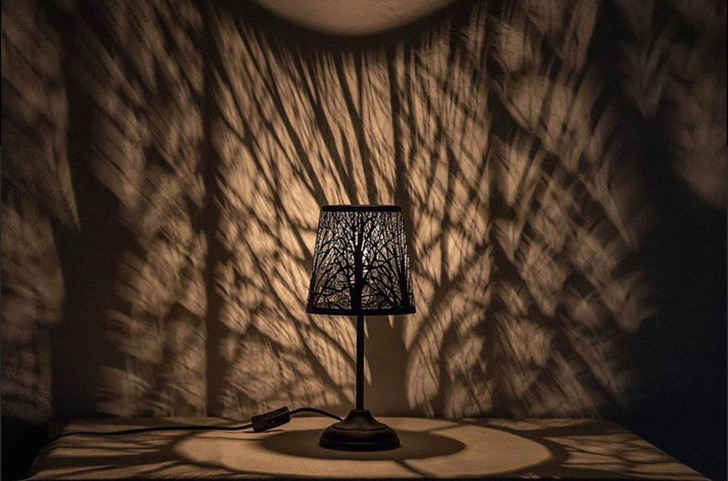 Hình ảnh chiếc đèn bàn tạo hiệu ứng đổ bóng rừng cây lên tường phòng