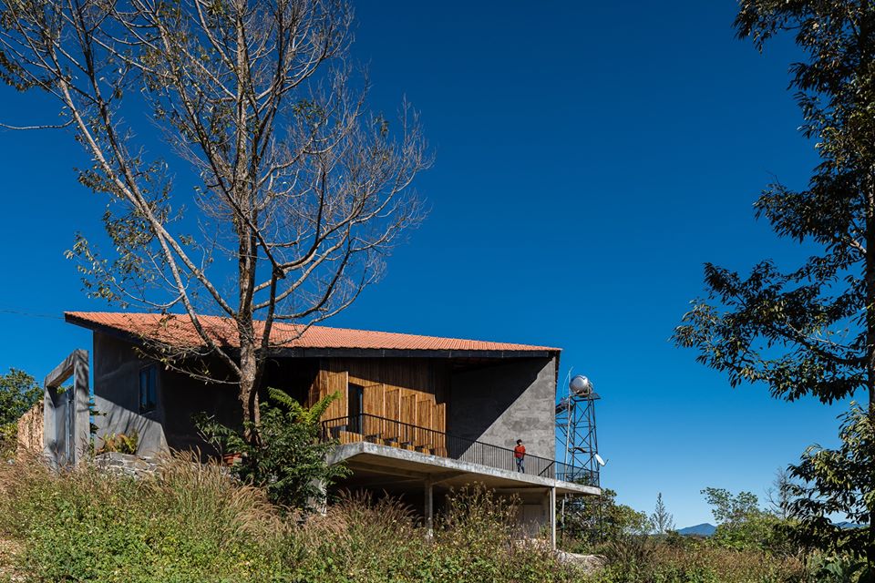 Hình ảnh cận cảnh mặt tiền ngôi nhà Gia Nghĩa với vật liệu gỗ chủ đạo, phía trước là thung lũng