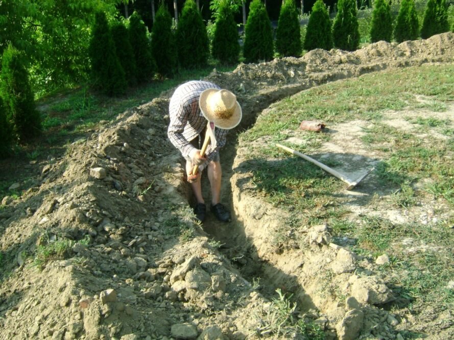 Hình ảnh một người đàn ông đang cuốc đất làm móng nhà hobbit