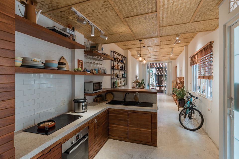 Hình ảnh không gian phòng bếp với kệ gỗ gắn tường, bàn đảo lát đá granite