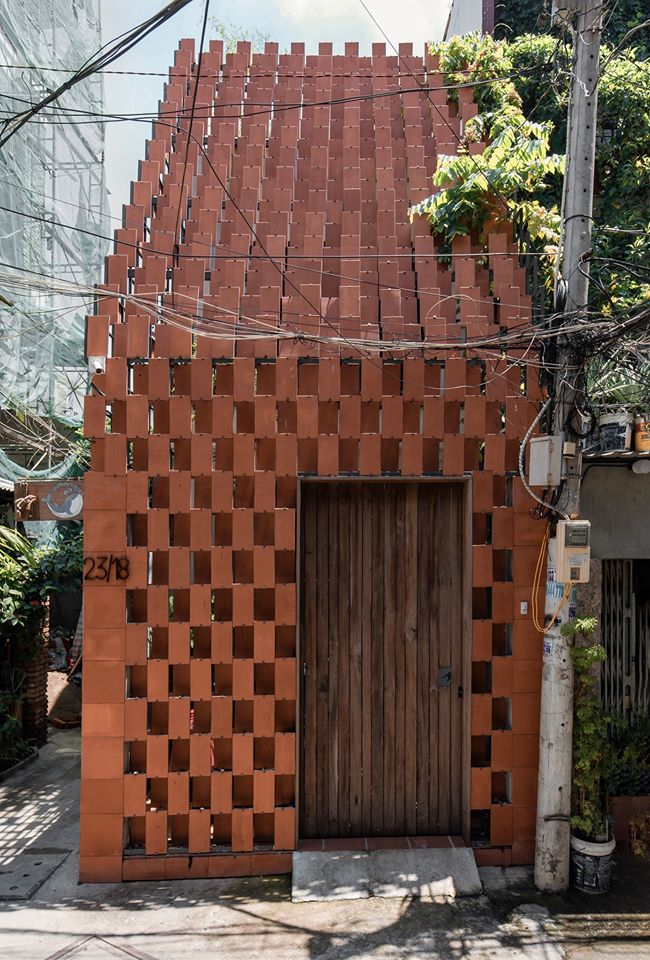 Hình ảnh cận cảnh mặt tiền nhà Phương với cửa gỗ tái chế, gạch nung truyền thống chủ đạo