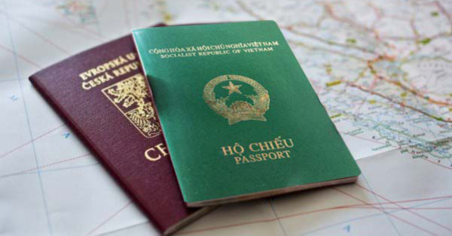 Hình ảnh hai cận cảnh hai cuốn hộ chiếu đặt trên tấm bản đổ, một cuốn màu nâu và một cuốn màu xanh