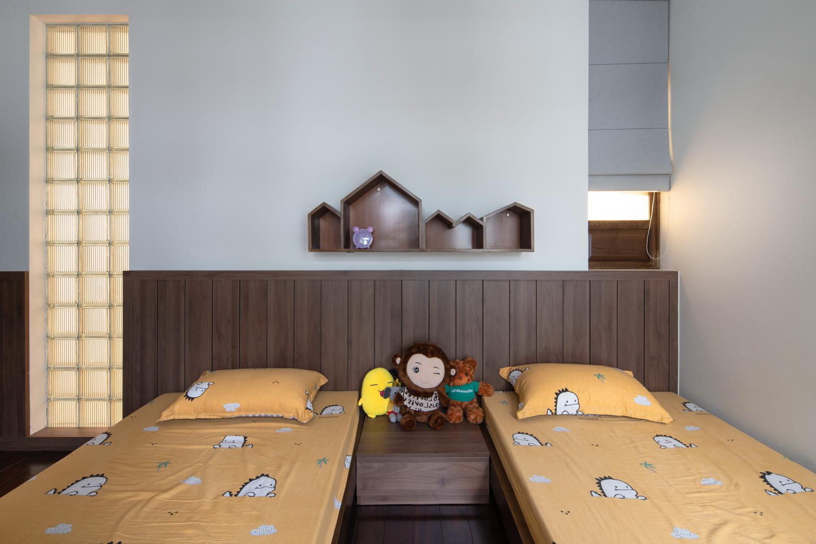 Hình ảnh phòng ngủ của các con được thiết kế đơn giản, chú trọng tính an toàn với giường đôi thấp gọn, mảng tường ốp gỗ sẫm màu.