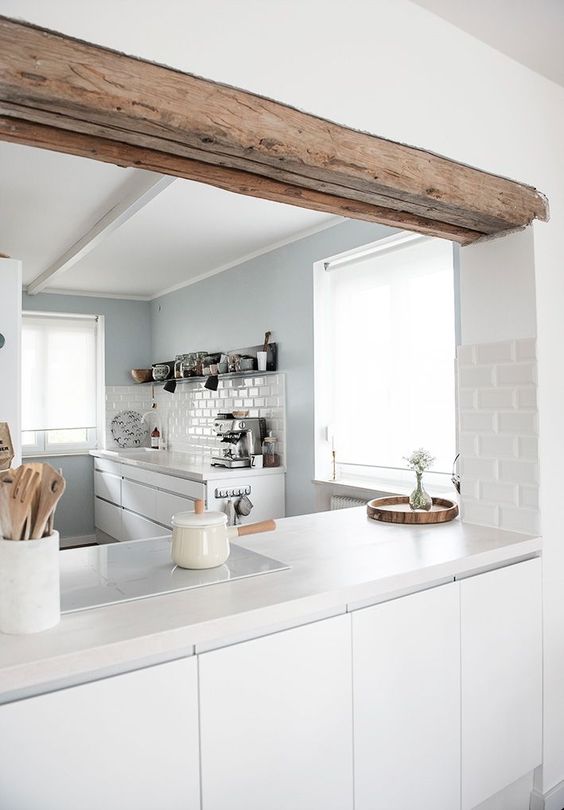 Hình ảnh một góc phòng bếp màu trắng chủ đạo với tủ lưu trữ không tay nắm, dầm gỗ mộc mạc