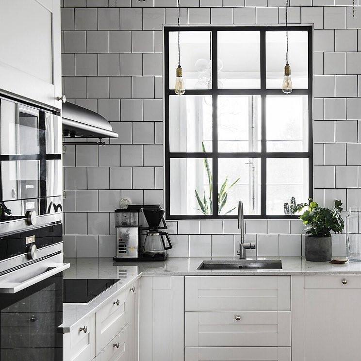 Hình ảnh góc bếp nhỏ màu trắng với cửa sổ kính khung đen bắt mắt, chậu cây trang trí, trang thiết bị hiện đại