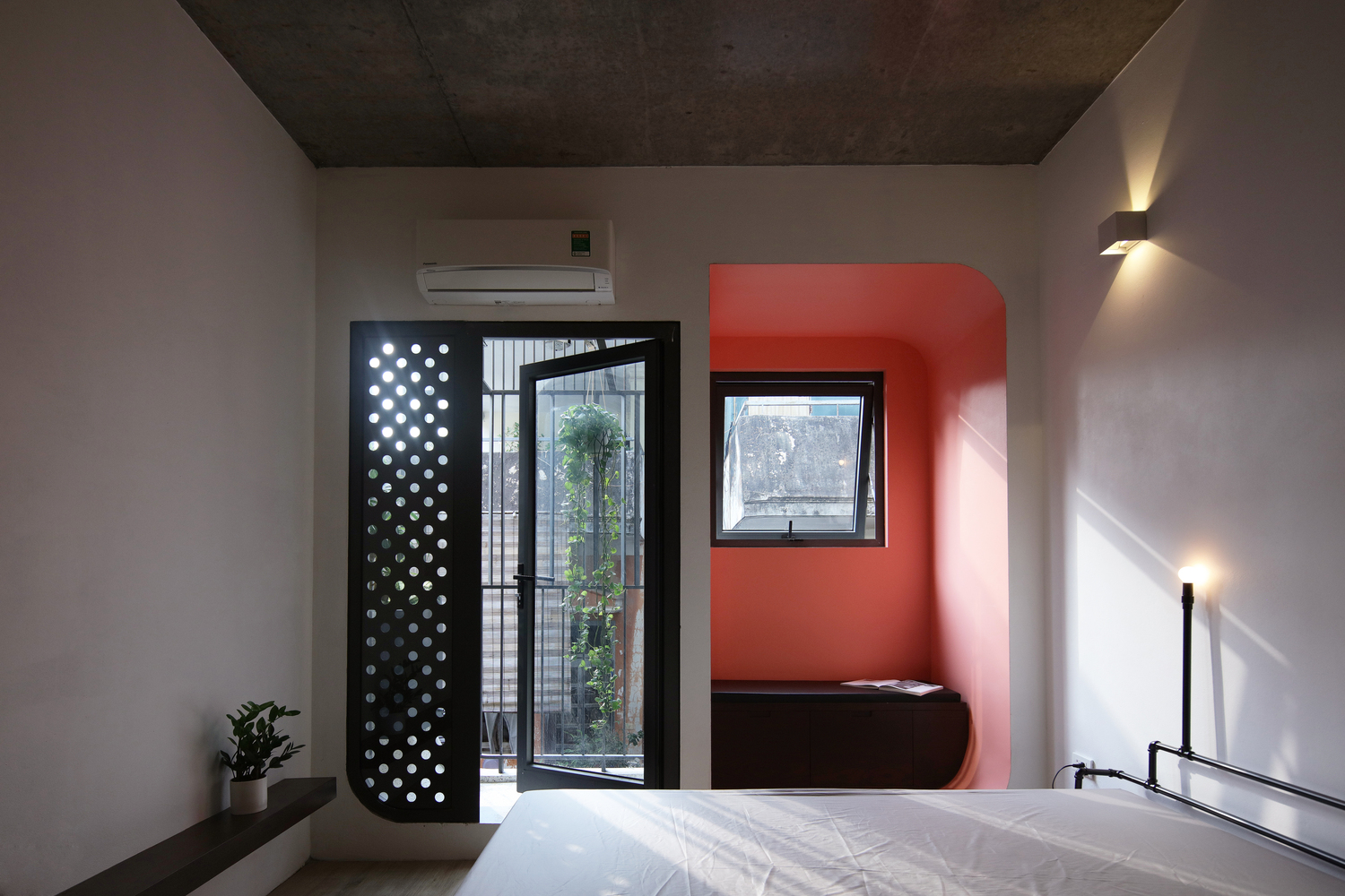 Hình ảnh phòng ngủ nhà phố Hà Nội với nội thất đơn giản, mảng tường màu đỏ cam nổi bật