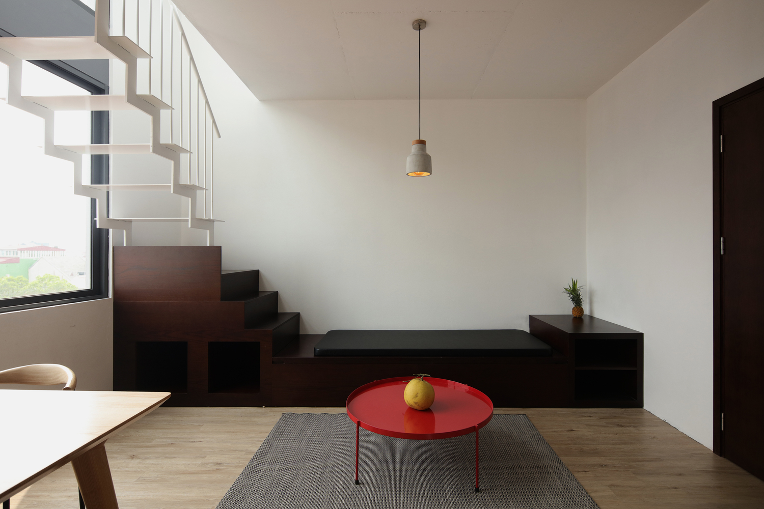 Hình ảnh phòng khách căn hộ cho thuê với thiết kế đơn giản, bàn trà màu đỏ nổi bật trên thảm trải màu xám