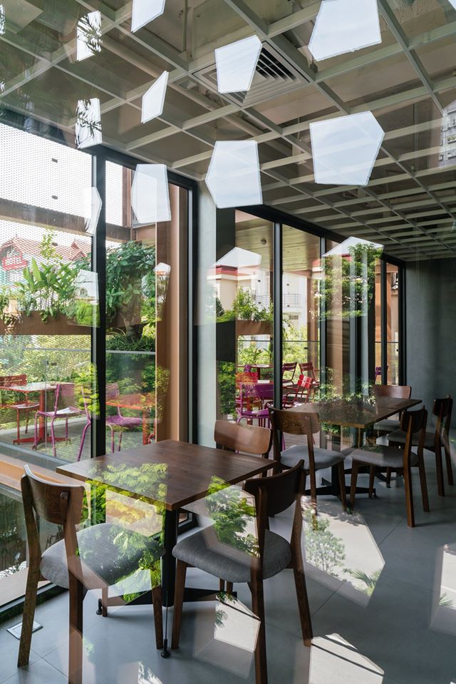 Hình ảnh một góc nhà hàng với những bộ bàn ghế bằng gỗ mộc mạc, tường kính trong suốt