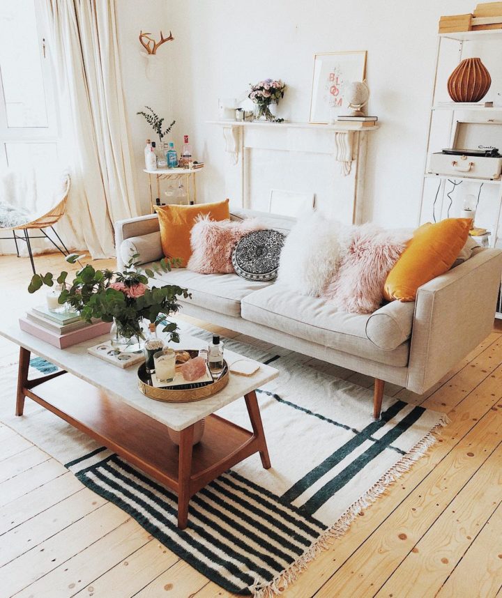 Hình ảnh phòng khách ngọt ngào với sofa trắng sữa, gối tựa lông hông phấn, cam, thảm trải kẻ sọc sinh động