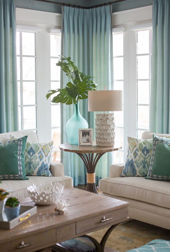Hình ảnh một góc phòng khách với ghế sofa màu sữa, rèm màu xanh bạc hà thanh lịch
