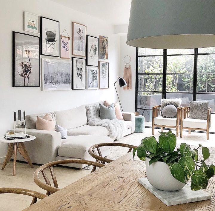 Hình ảnh phòng khách hiện đại, thoáng sáng với sofa trắng, cửa kính khung đen, tranh treo tường ấn tượng