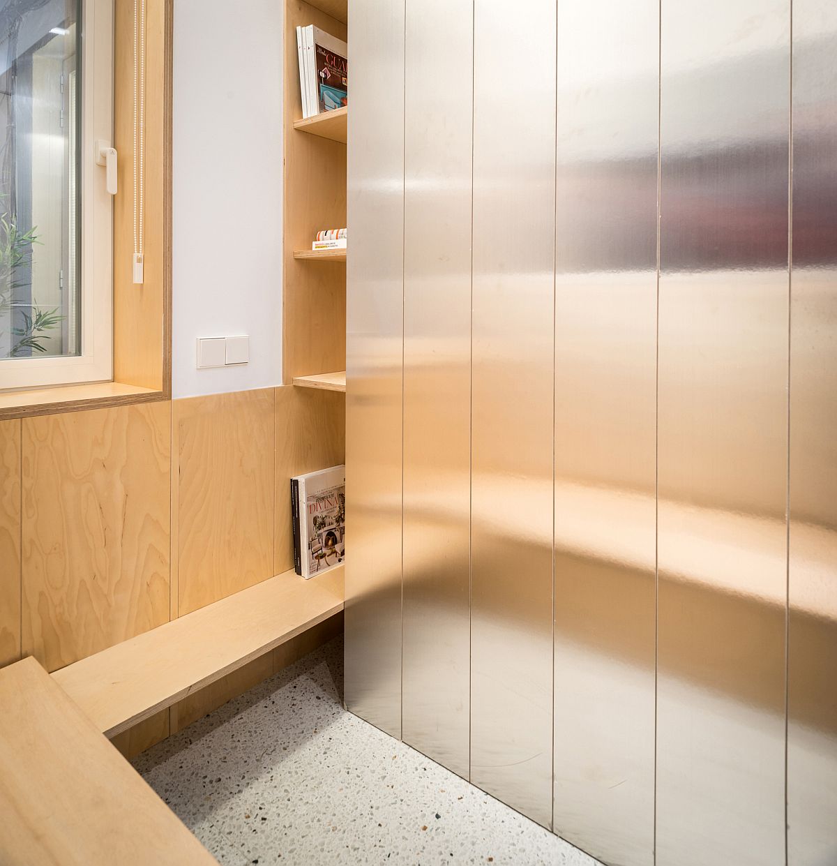 Hình ảnh cận cảnh một góc hệ tủ tường bằng thép phản chiếu ánh sáng, bên cạnh là tủ gỗ thông ấm áp