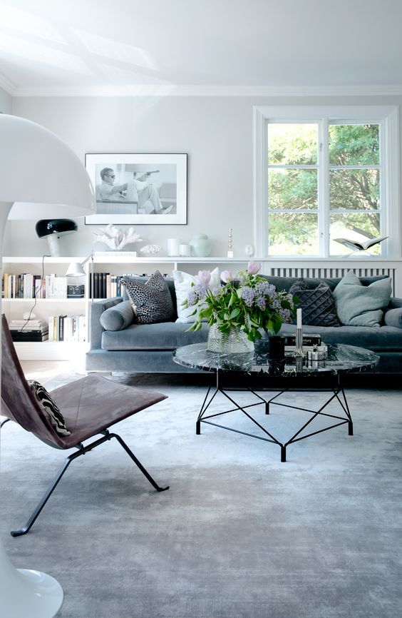 Hình ảnh phòng khách thanh lịch với sofa xám nhạt, bàn trà kính lớn, tranh treo tường ấn tượng