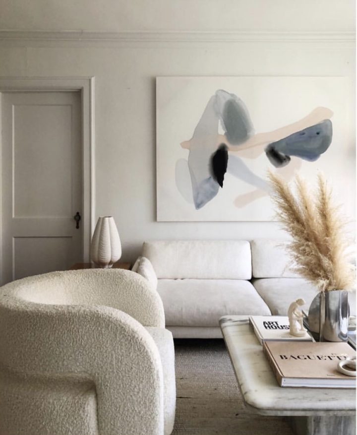 Hình ảnh một góc phòng khách màu be với sofa màu sữa, tranh nghệ thuật treo tường
