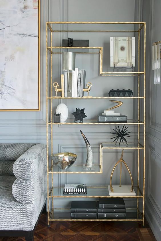 Hình ảnh một góc phòng khách nổi bật với khung tranh treo tường và giá bày đồ trang trí được mạ vàng bóng bẩy.