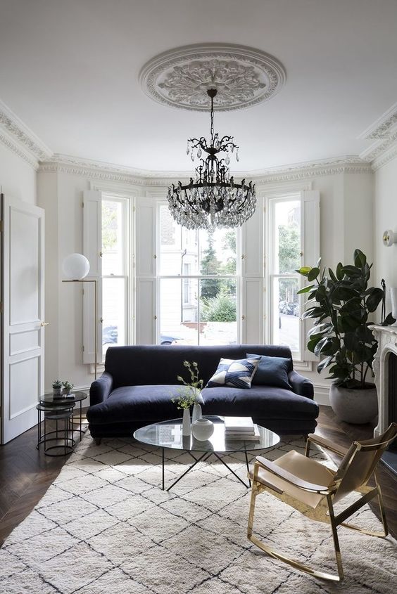 Hình ảnh phòng khách phong cách Bắc Âu sang trọng với sofa xanh than, thảm trải màu sữa trang nhã, bàn trà kính trong suốt