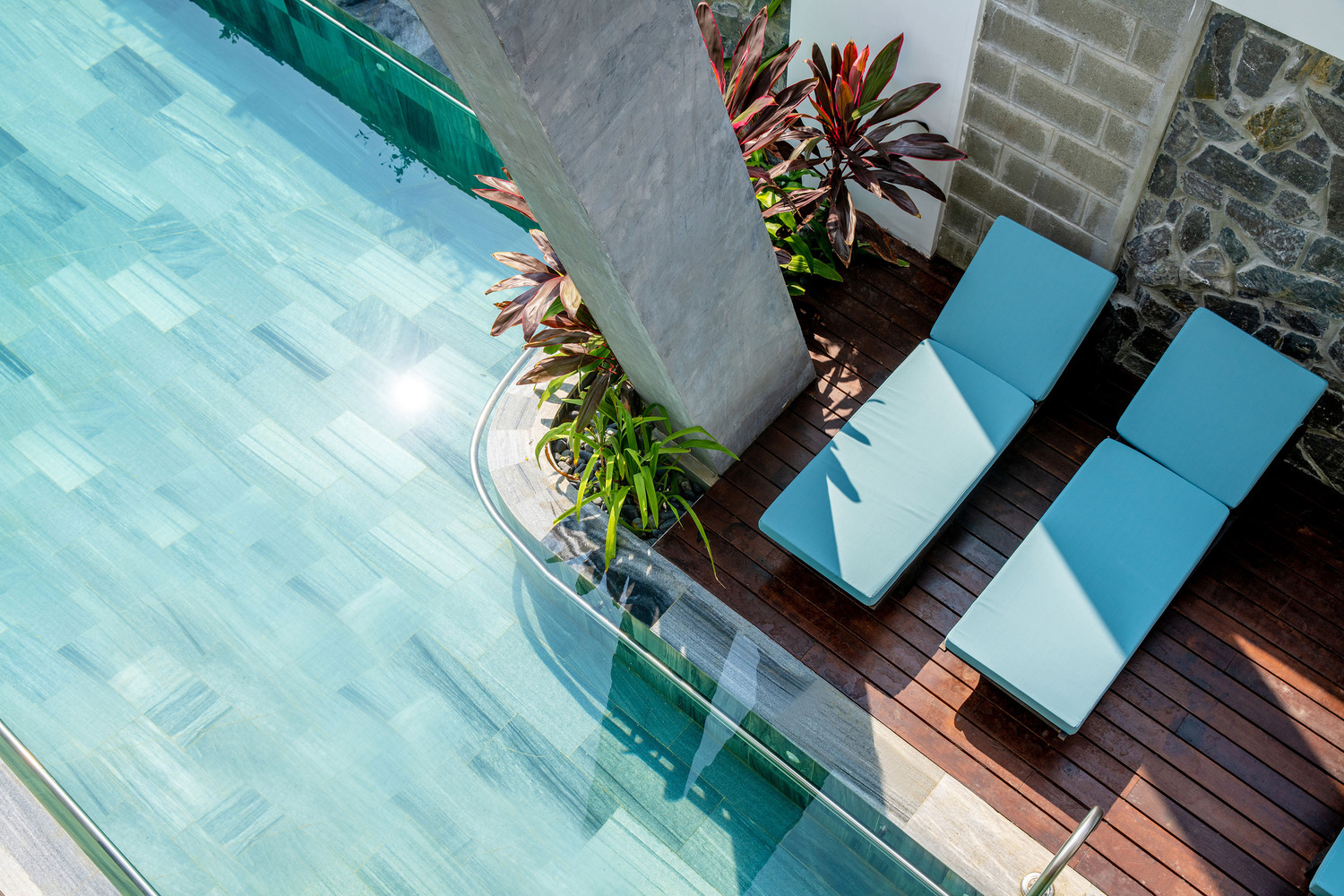 Hình ảnh cận cảnh góc thư giãn, ghế tắm nắng lý tưởng cạnh bể bơi trong xanh.