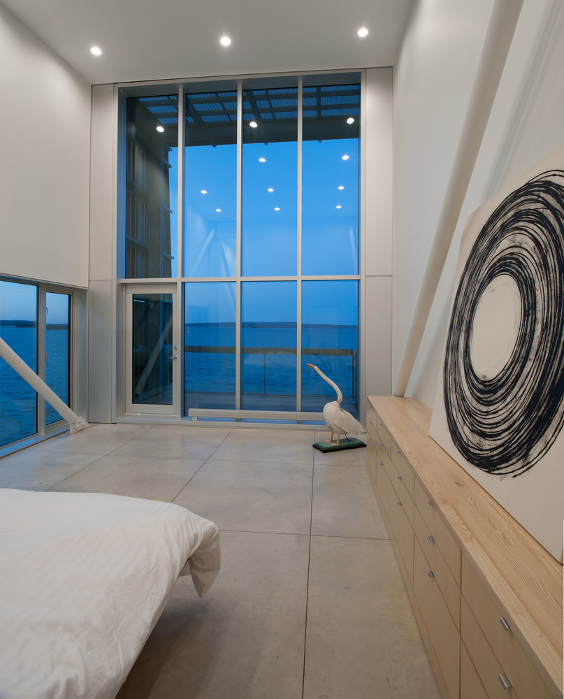Hình ảnh cận cảnh một góc phòng ngủ với giường nệm màu trắng, tường vẽ hình tròn đen, cửa kính trong suốt hướng ra biển
