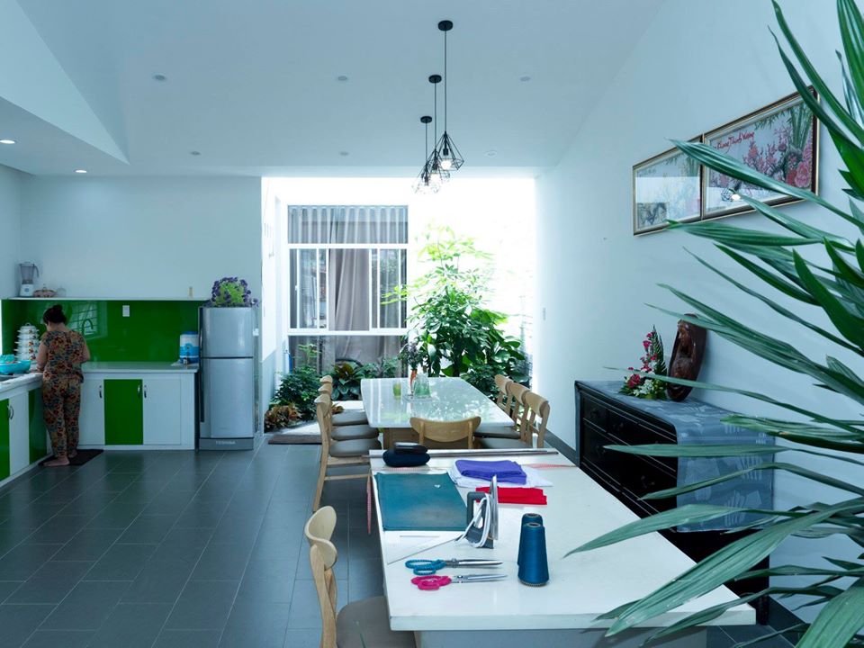 Hình ảnh toàn cảnh phòng bếp với tường và tủ màu xanh lá cây, cạnh đó là bộ bàn ăn ấm áp, góc làm việc gọn gàng