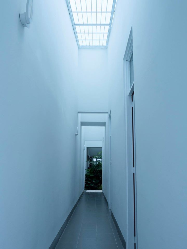 Hình ảnh cận cảnh hành lang nhà 1 tầng với mái kính trong suốt, tường sơn trắng, nền lát gạch xám