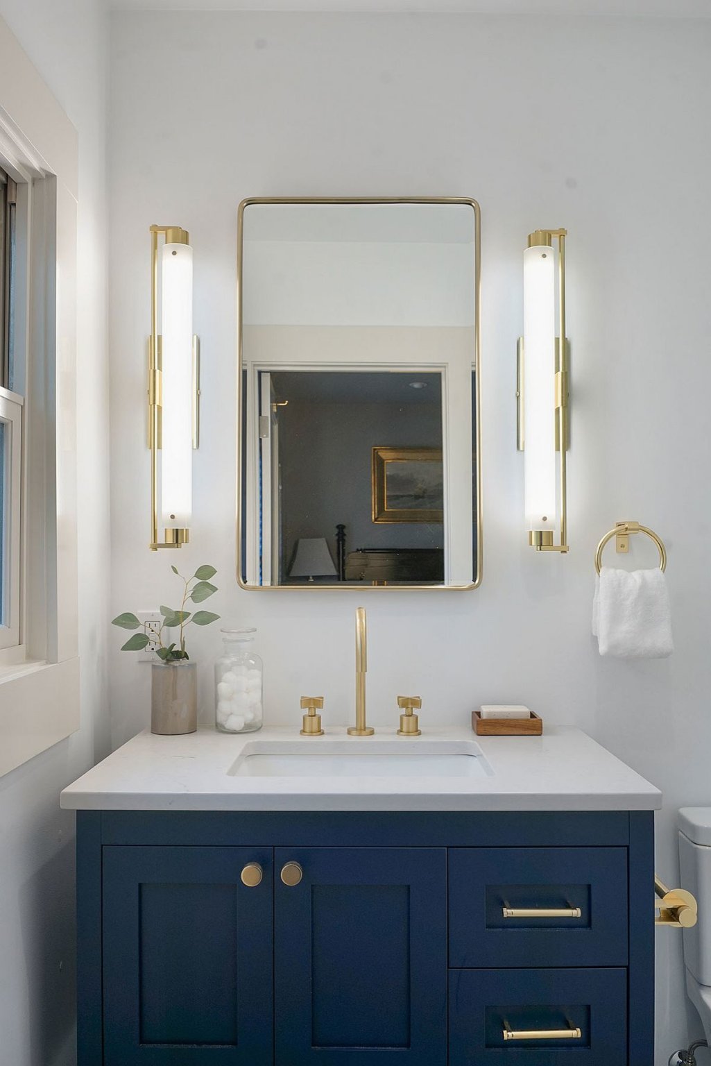 Hình ảnh một góc phòng tắm với tủ màu xanh dương, gương lớn, tay nắm vàng đồng