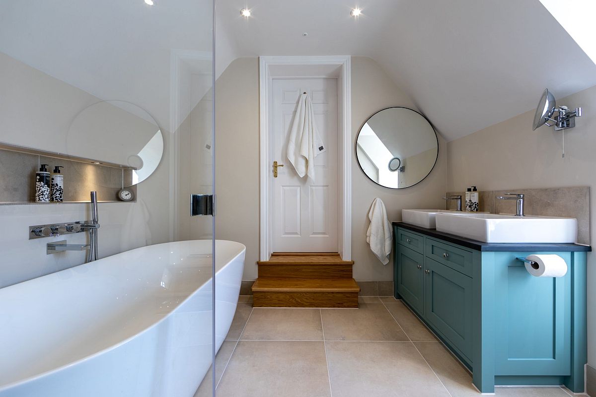 Hình ảnh phòng tắm tầng áp mái với bồn tắm lớn, tủ lưu trữ màu xanh pastel, bồn rửa đôi hình vuông