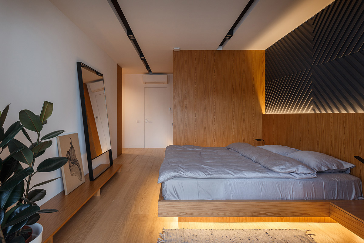 Hình ảnh phòng ngủ với giường phản lơ lửng, đèn LED gắn phía dưới giường, tường đầu giường trang trí ấn tượng, đôi diện là tranh nghệ thuật, chậu cây xanh mướt