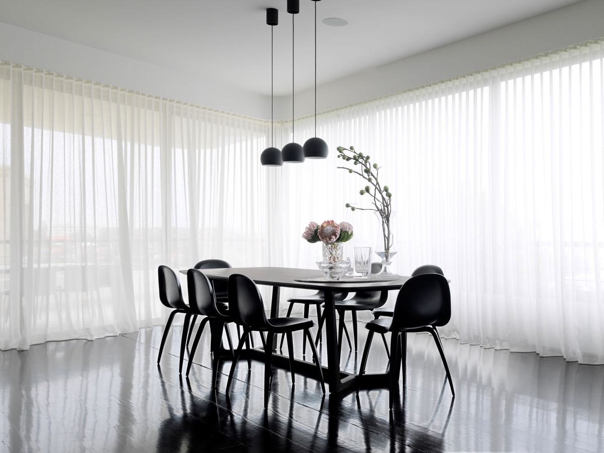 Hình ảnh phòng ăn với bàn ghế, sàn nhà,đèn thả màu đen, bao xung quanh là rèm cửa màu trắng