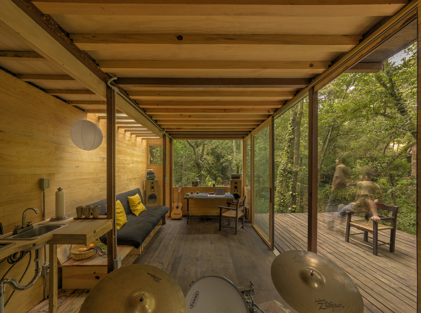 Hình ảnh không gian sinh hoạt thoáng đãng, nội thất tinh giản bên trong ngôi nhà gỗ giữa rừng cây.