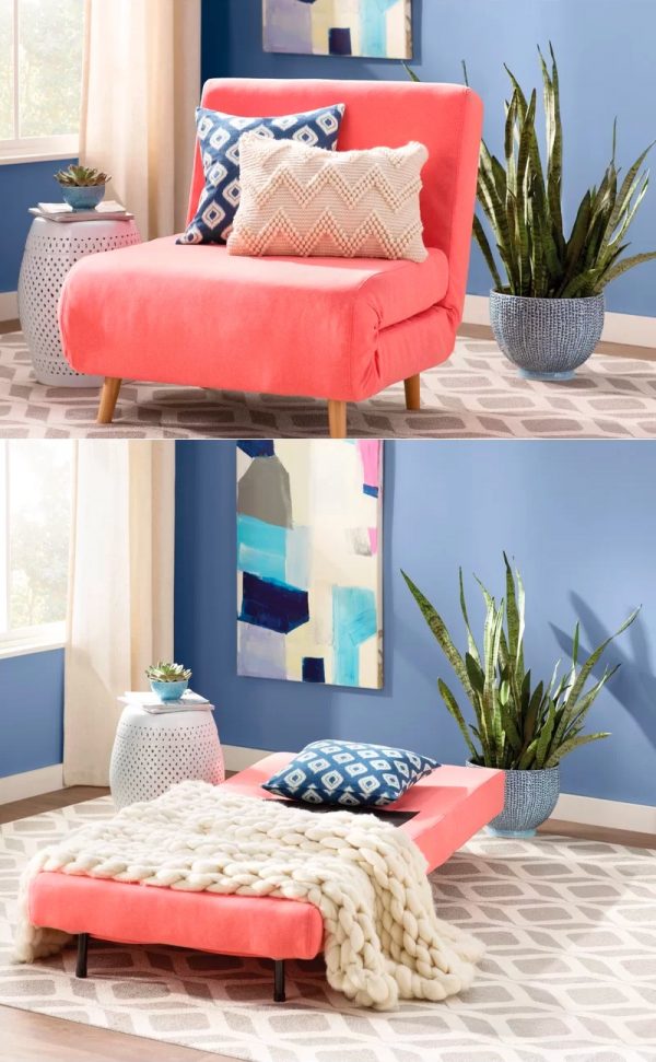 Hình ảnh cận cảnh ghế ngủ màu hồng san hô kết hợp chăn trắng, gối họa tiết xanh - trắng, cạnh đó là chậu cảnh, tranh treo tường trang trí