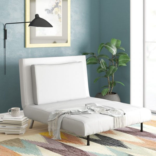 Hình ảnh ghế ngủ màu trắng đặt cạnh bức tường sơn xanh, hai bên là chồng sách, chậu cảnh, trang trí bằng tranh treo tường, đèn màu đen