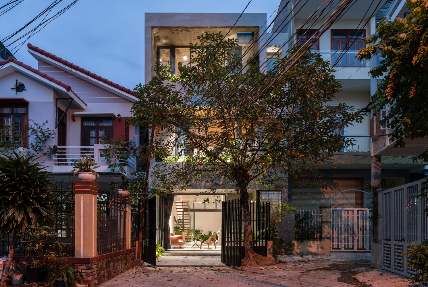 Hình ảnh toàn cảnh ngôi nhà Bin & Bon với vật liệu kính chủ đạo nơi mặt tiền, cây xanh lớn 