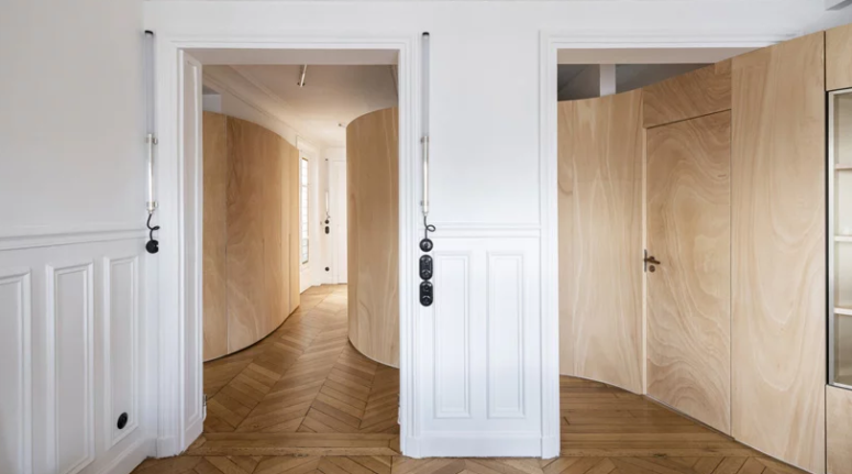 Cận cảnh lối hành lang trong căn hộ ở Paris với sàn gỗ xương cá, tường gỗ uốn lượn, cửa cổ điển.