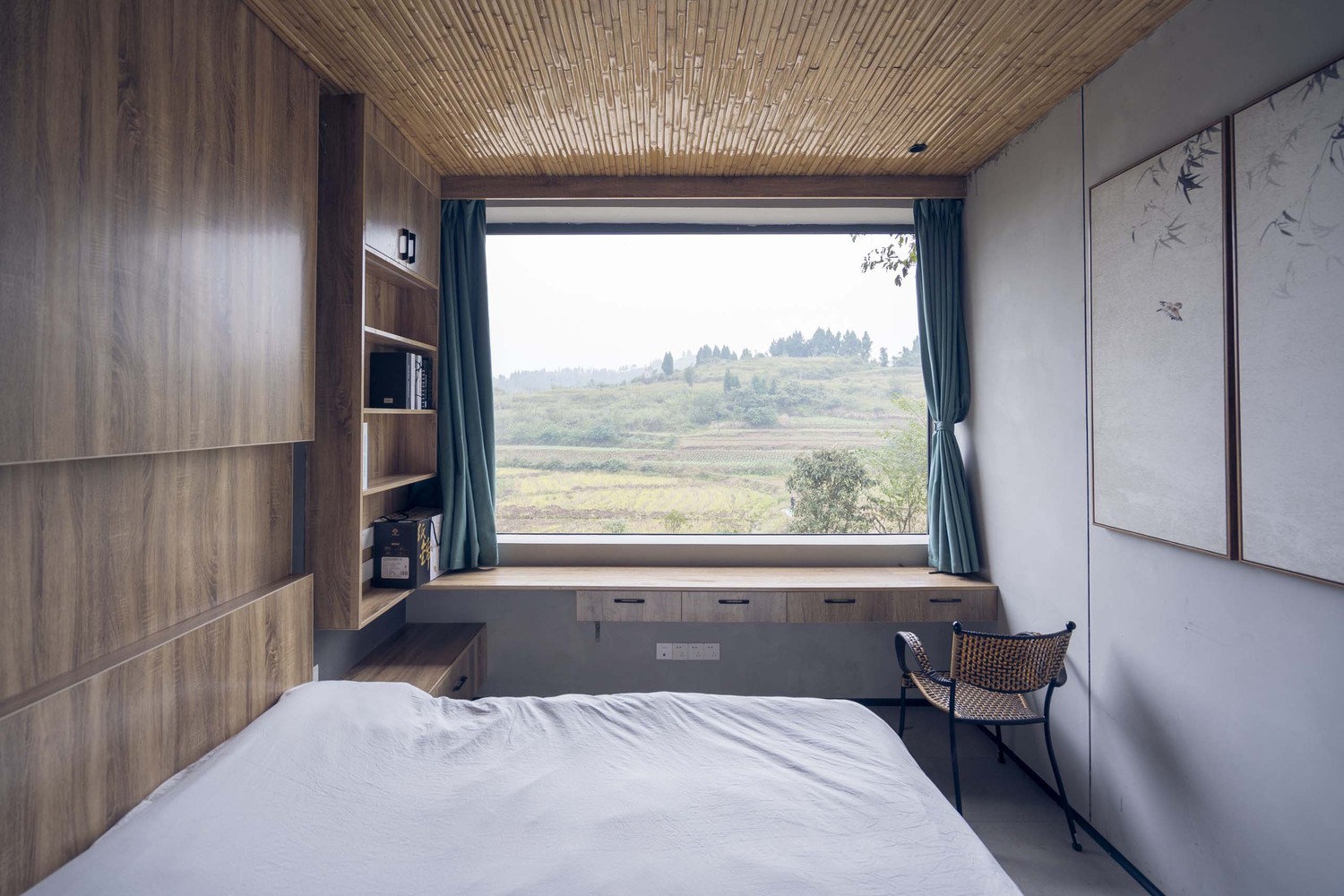Hình ảnh phòng ngủ với ga gối màu trắng, tủ gỗ, cửa sổ kính nhìn ra núi rừng
